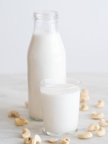 Foto de perfil de una botella y un vaso con leche de anacardos casera