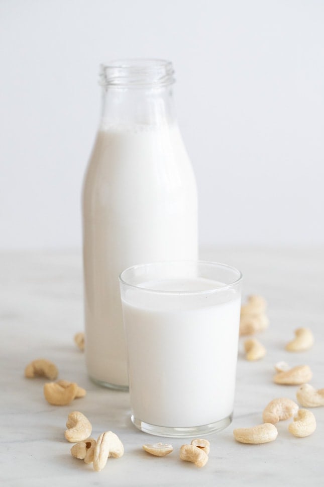 Foto de perfil de una botella y un vaso con leche de anacardos casera