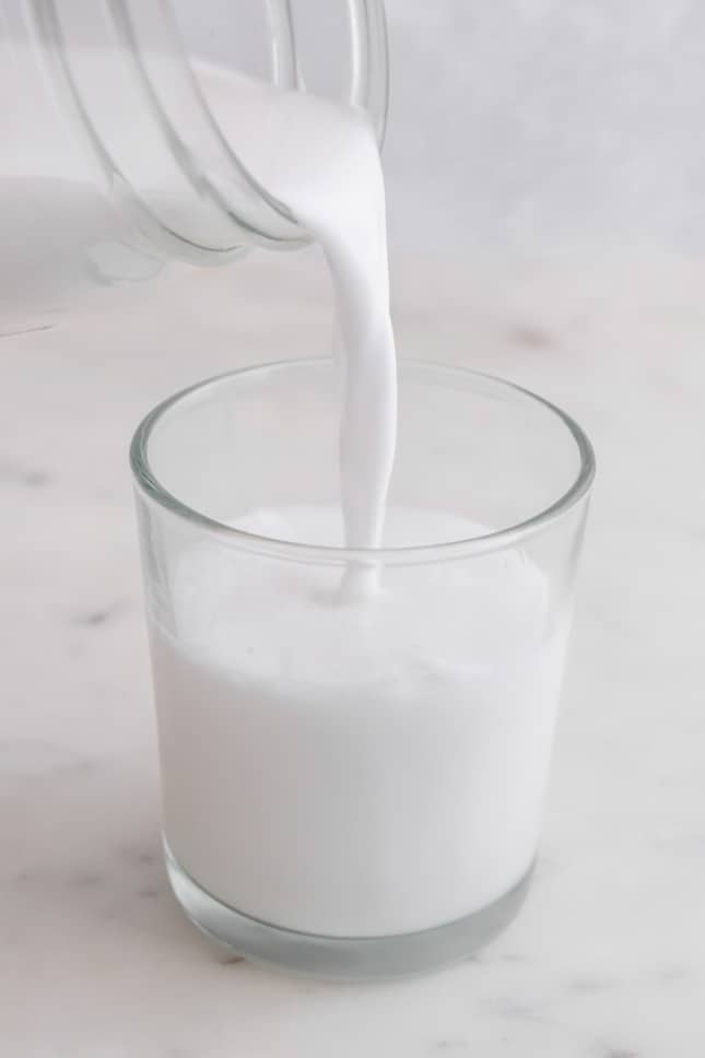 Foto de una jarra vertiendo leche de coco en un vaso
