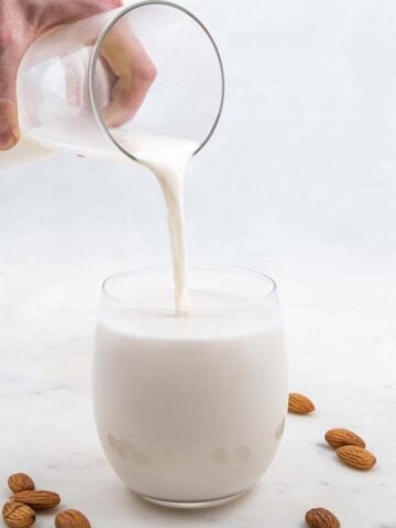 Foto de perfil de un vaso llenándose de leche de almendras