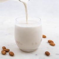 Foto cuadrada de un vaso llenándose de leche de almendras
