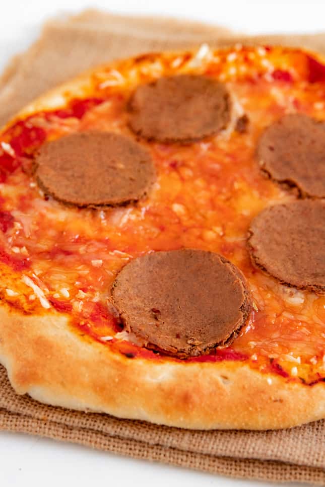 Foto de unas rodajas de pepperoni vegano como topping de una pizza vegana