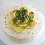 Tarta de limón vegana encima de una base para tartas con las palabras tarta de limón vegana.