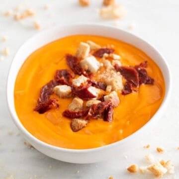 Bol de salmorejo adornado con picatostes y trozos de tomates secos.