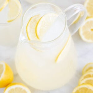 Jarra con limonada casera y limones alrededor.