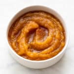 Compota de manzana en un bol con canela molida por encima.