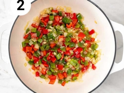 Olla con cebolla, ajos, pimiento verde y pimiento rojo salteados en aceite de oliva.