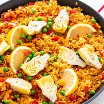 Paella de verduras con gajos de limón por encima.