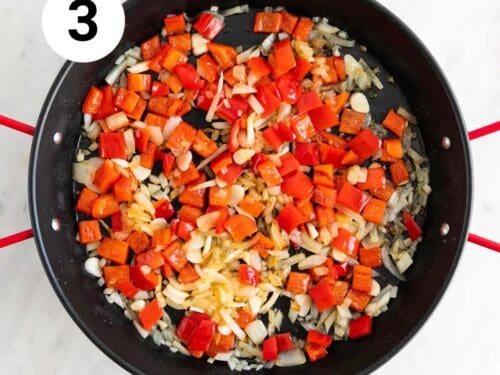 Cebolla, pimiento rojo y ajo sofritos en una paellera.