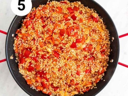 Verduras cocinadas y arroz antes de cocinarse en una paellera.