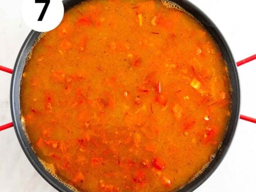 Verduras, arroz caldo, sal y pimienta en una paellera.