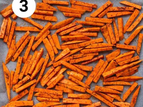 Bastones de boniato con aceite y especias en una bandeja para horno.