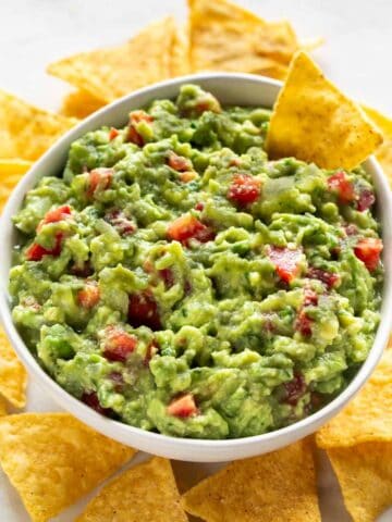 Bol de guacamole casero con nachos alrededor.