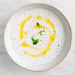 Salsa de yogur en cuenco con decoración de aceite de oliva y menta.