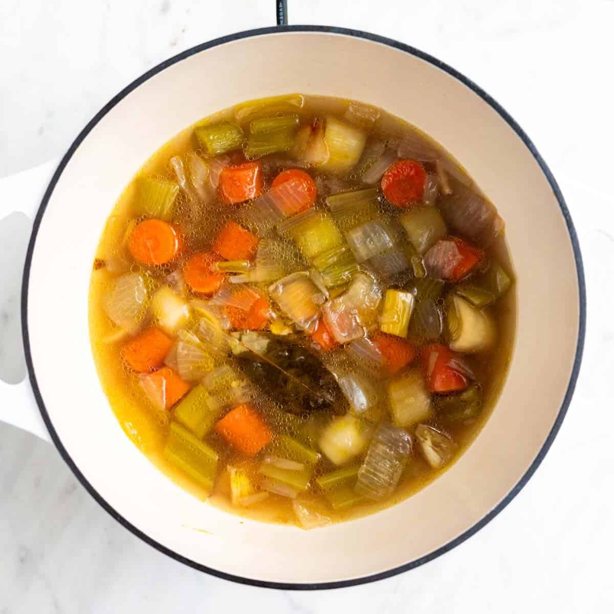Caldo de verduras cocinado en una olla antes de colar las verduras.