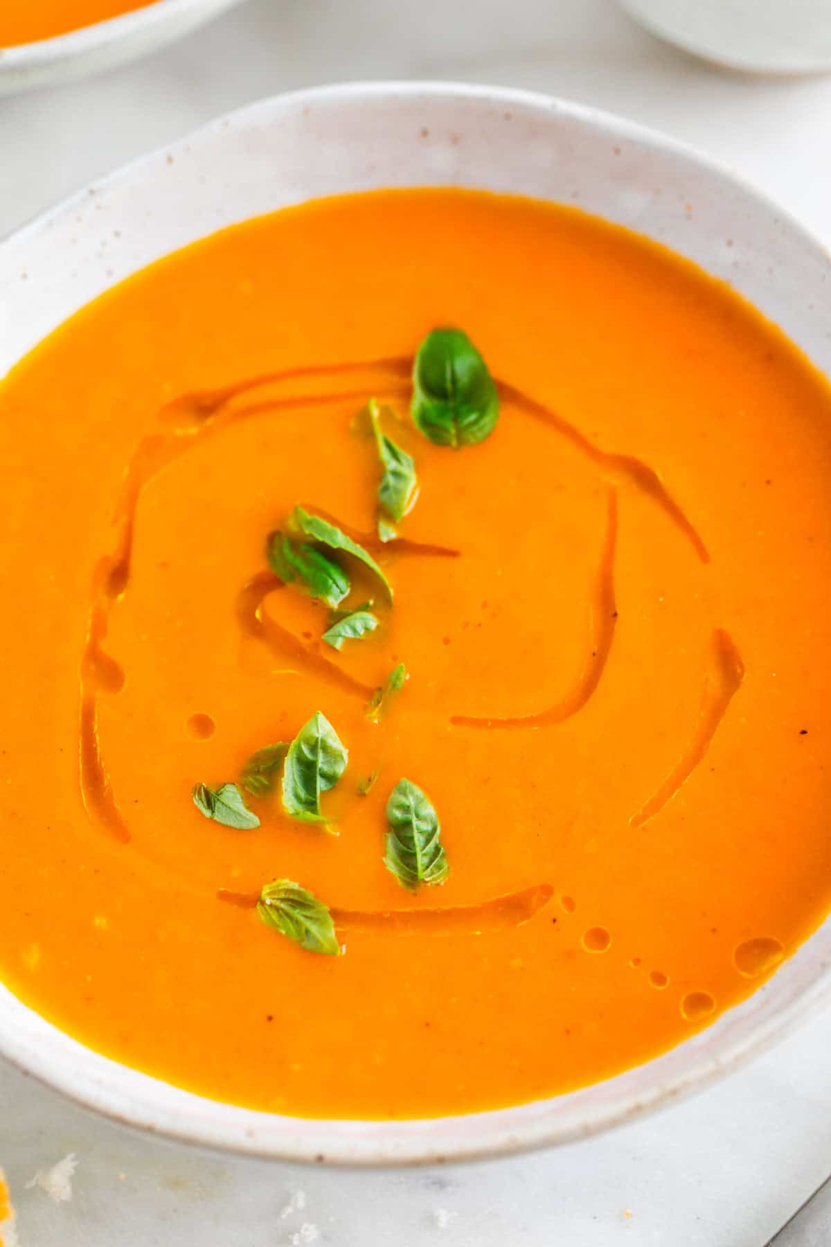 Bol con sopa de tomate decorado con albahaca y un chorrito de aceite.