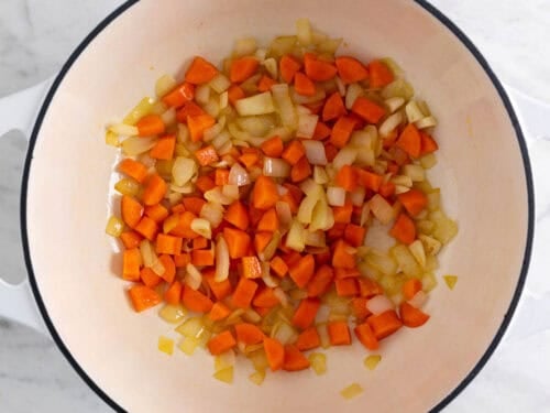 Ajo, cebolla y zanahoria salteados en una olla.