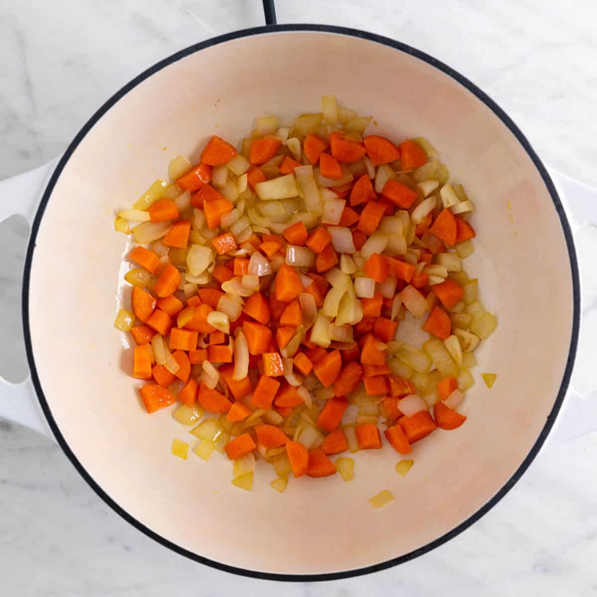 Ajo, cebolla y zanahoria salteados en una olla.