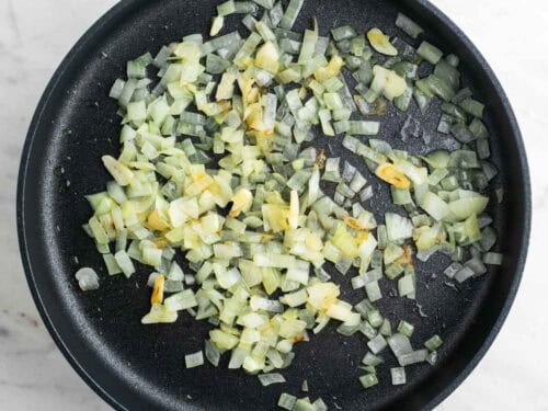 Sartén con cebolla y ajo cocinados.
