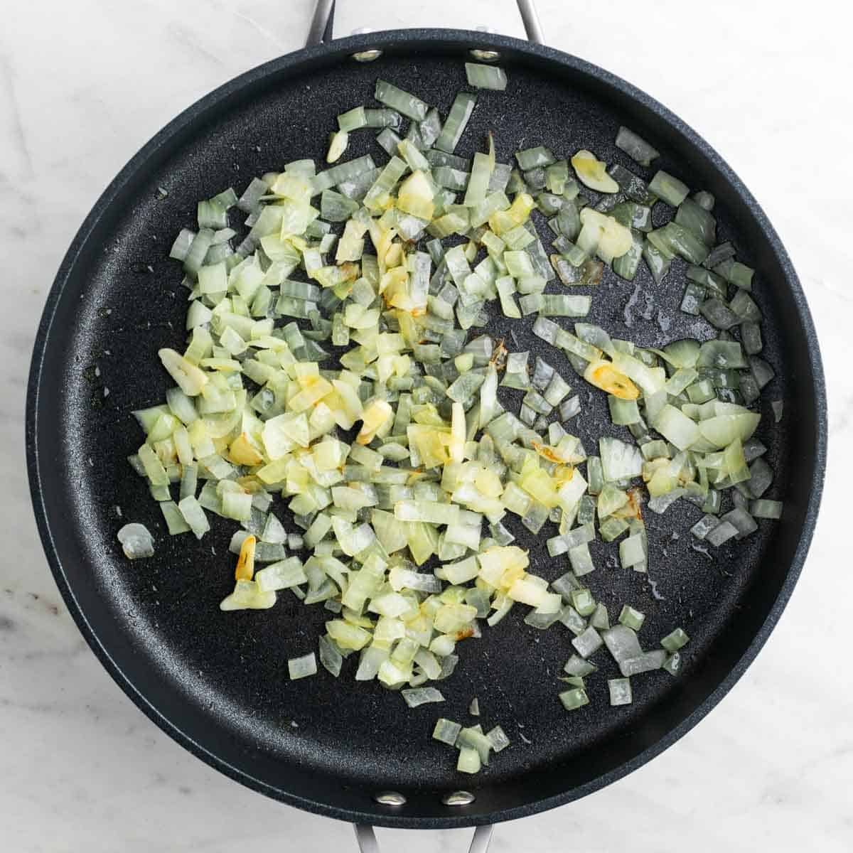 Sartén con cebolla y ajo cocinados.
