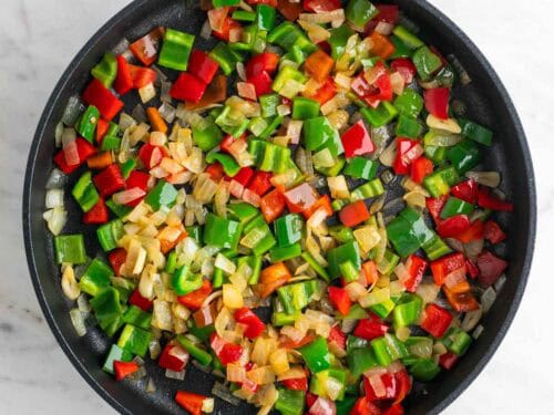 Sartén con cebolla, ajo y pimientos cocinados.