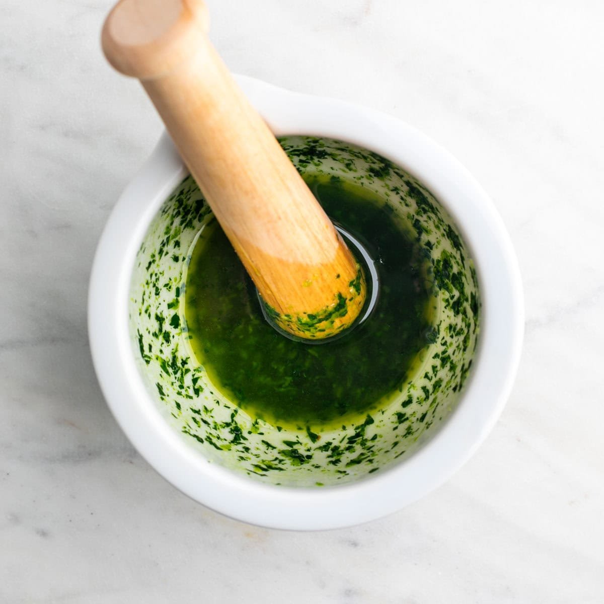 Salsa de ajo, perejil y aceite en un mortero.