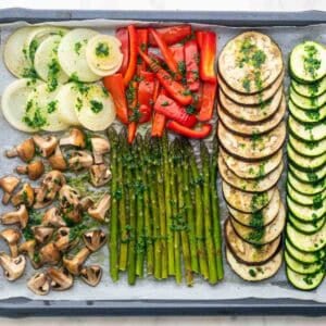 Verduras en una bandeja con la salsa por encima antes de hornearse.