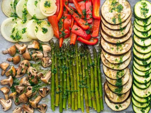 Verduras en una bandeja con la salsa por encima antes de hornearse.