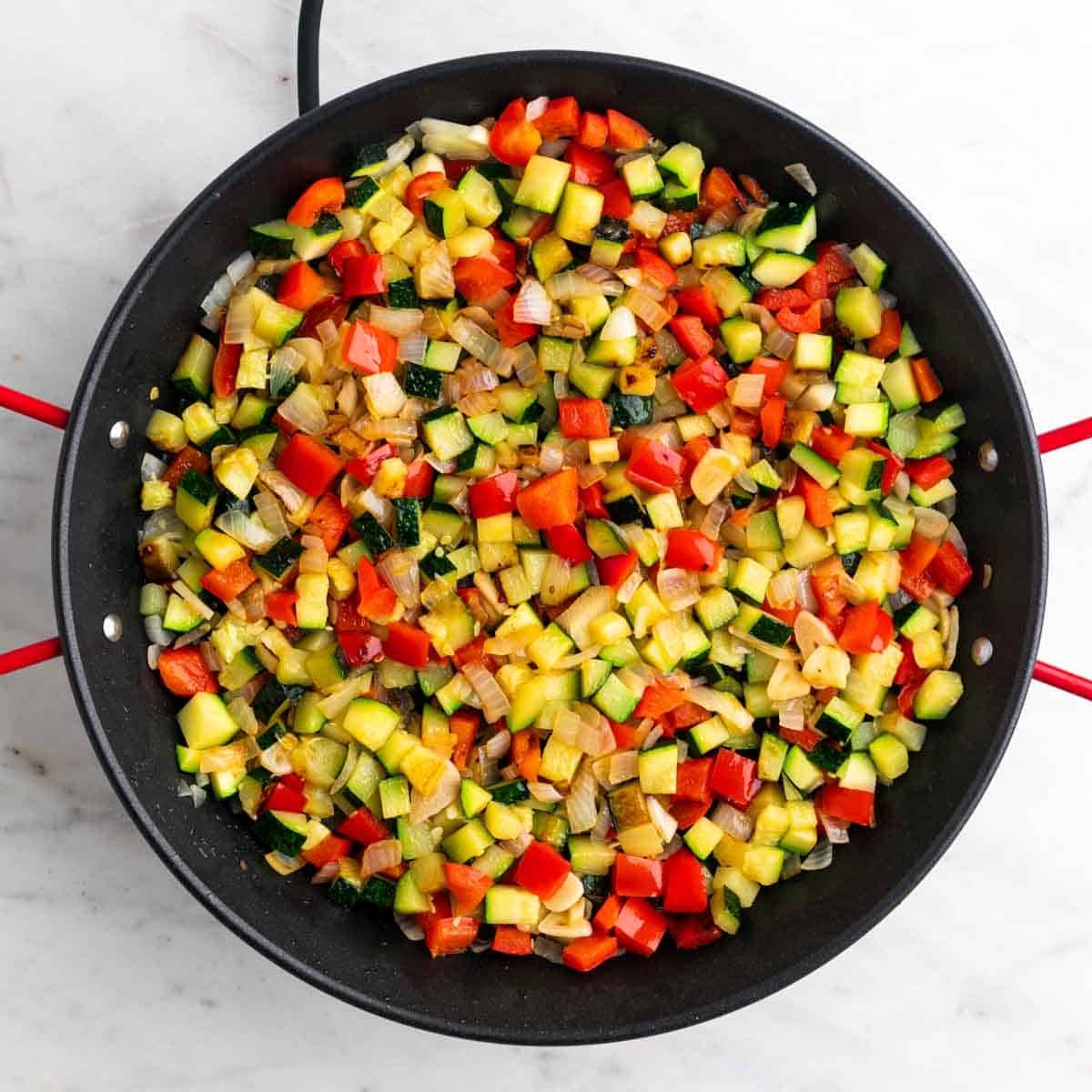 Verduras sofritas en una paellera.