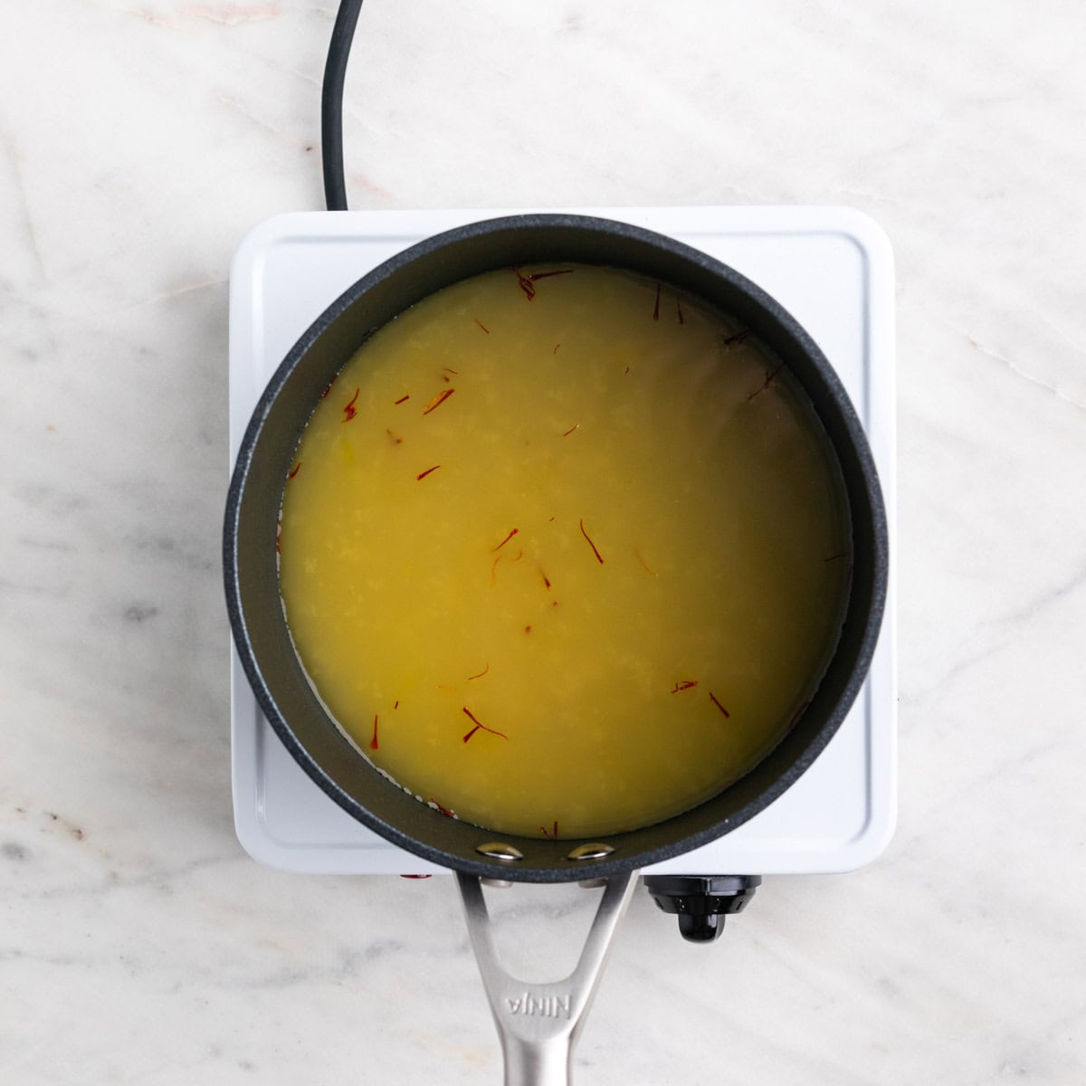 Caldo de verduras con azafrán en un cazo.