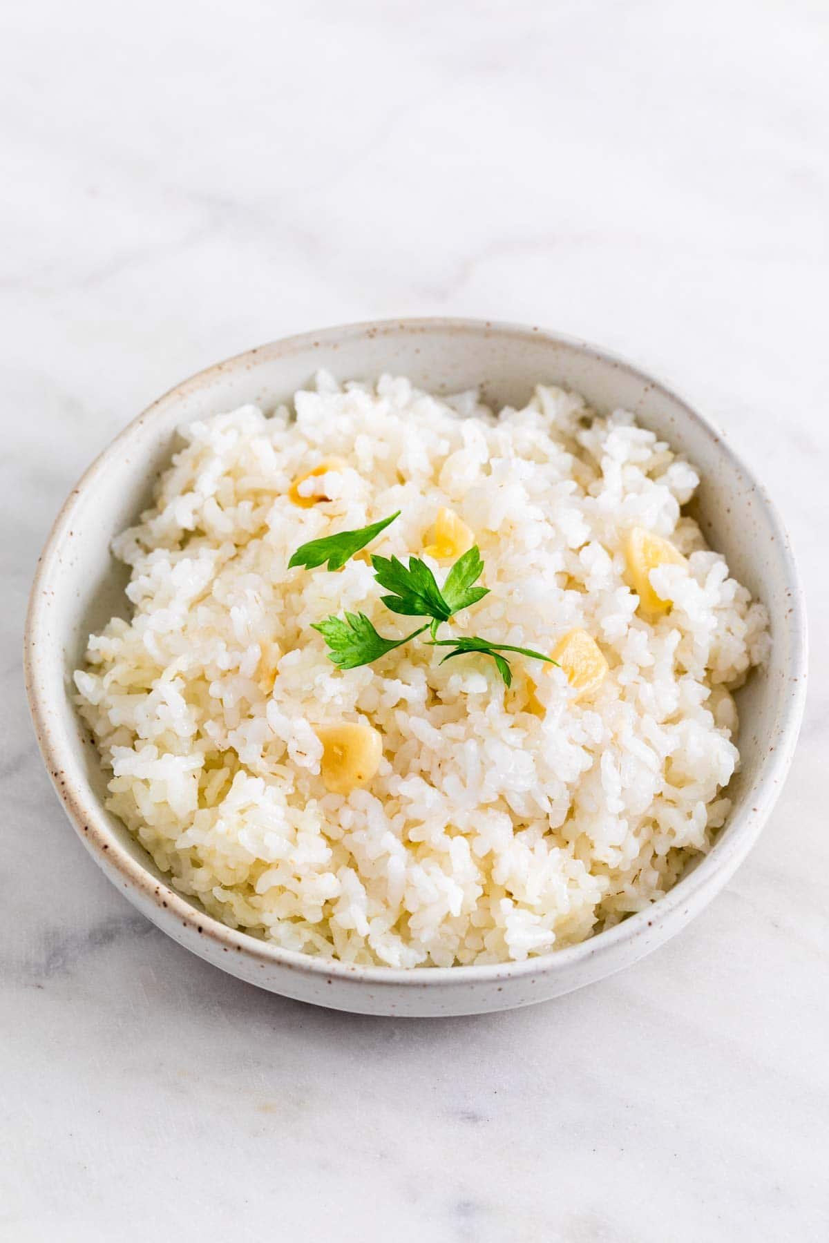 Arroz blanco servido en un bol y decorado con perejil fresco.