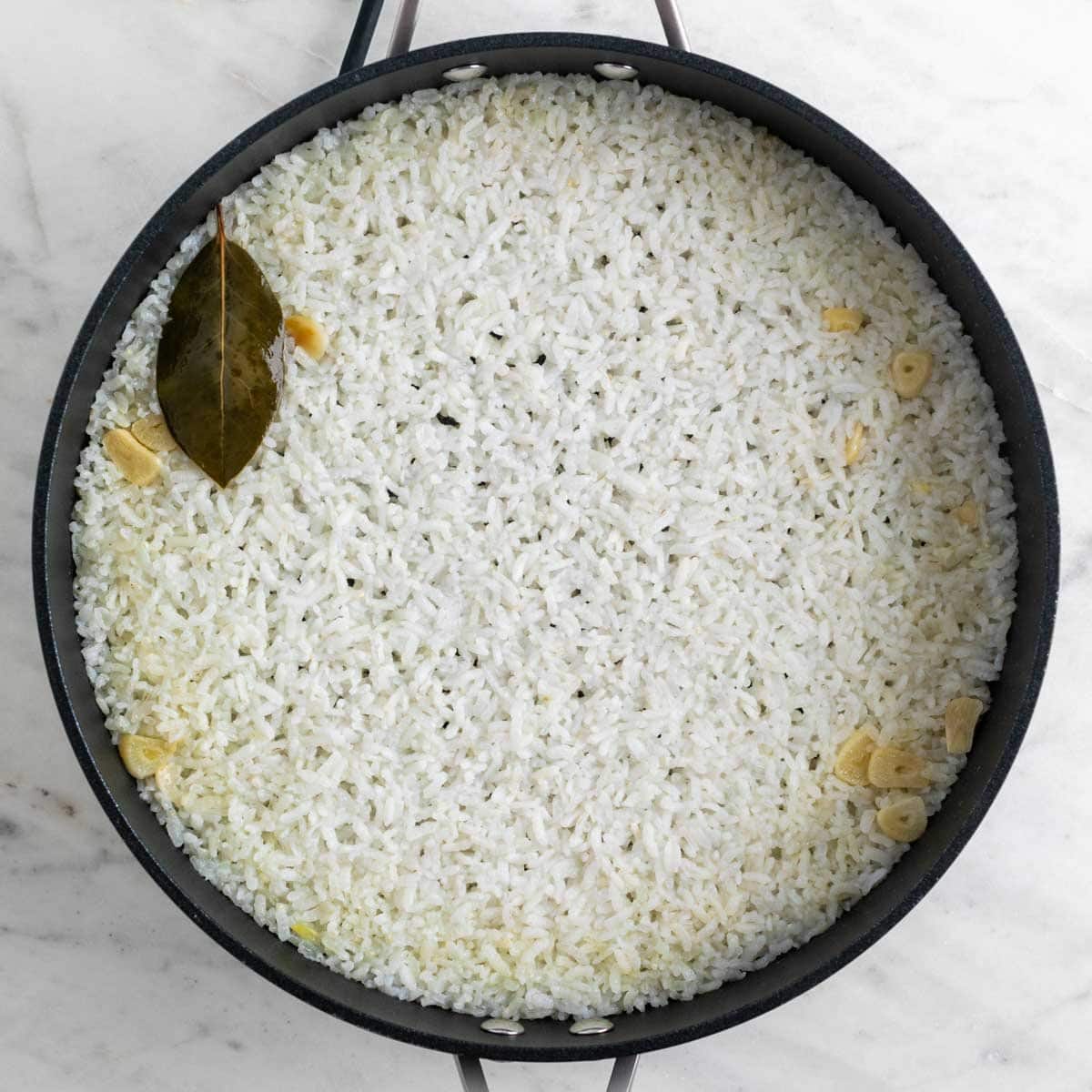 Arroz blanco cocinado en una sartén antes de reposar.