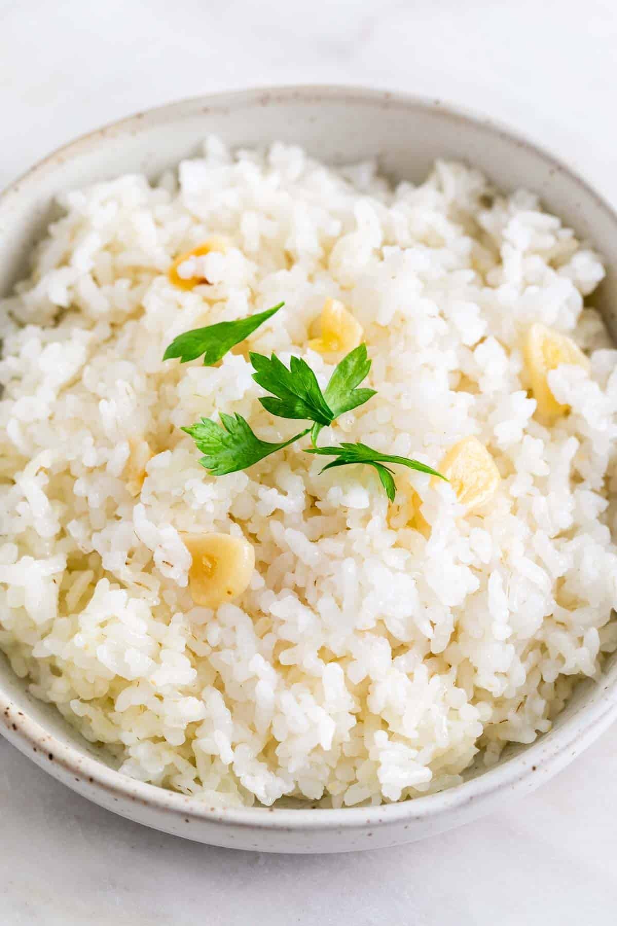 Arroz blanco cocinado en un bol con perejil por encima.