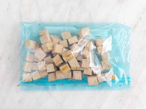 Dados de tofu con salsa de soja en una bolsa de congelación.