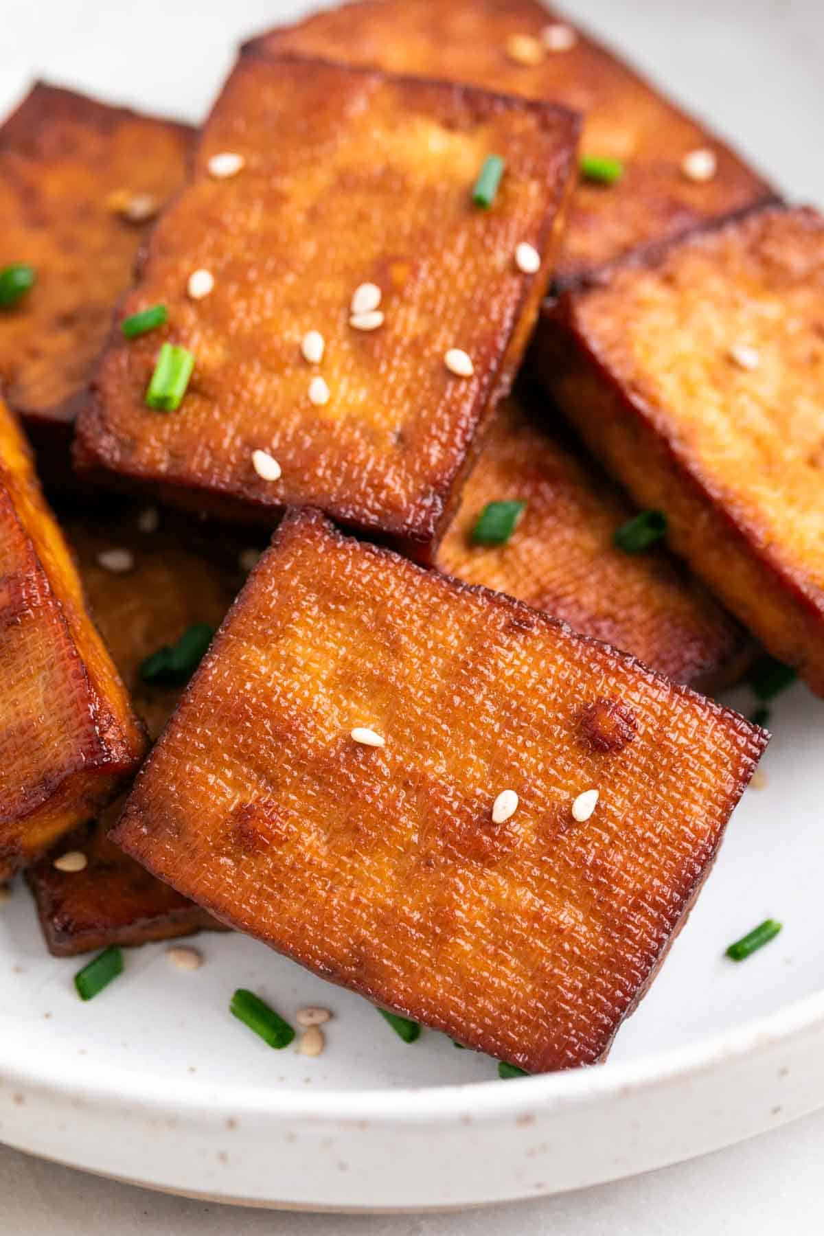 Plato con tofu ahumado decorado con cebollino y sésamo.