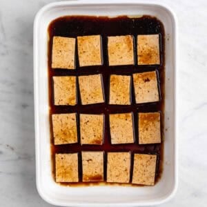 Las rodajas de tofu con el marinado en una fuente.