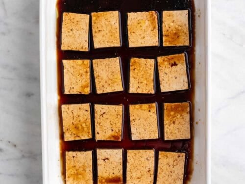 Las rodajas de tofu con el marinado en una fuente.