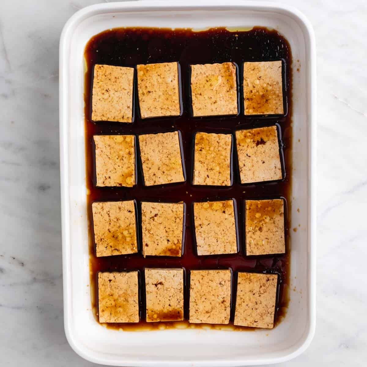 Las rodajas de tofu con el marinado en una fuente.