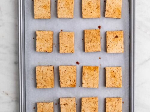 Tofu marinado en una bandeja con papel de horno.