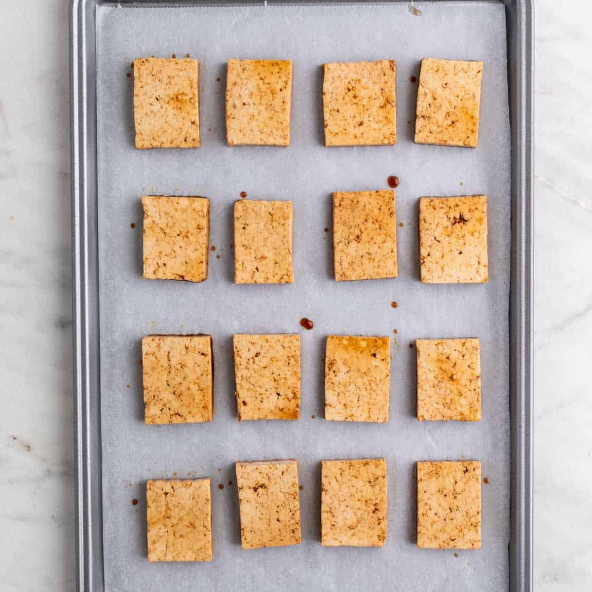 Tofu marinado en una bandeja con papel de horno.
