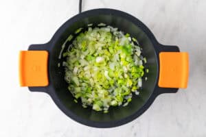 Cebolla, puerro y ajo salteados en una cacerola.