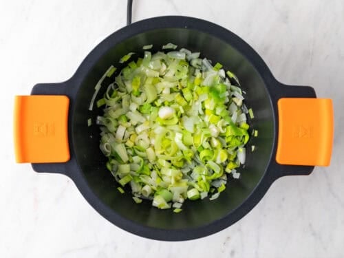 Cebolla, puerro y ajo salteados en una cacerola.