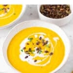 Boles de crema de verduras servidos con leche de coco, perejil y semillas de calabaza.