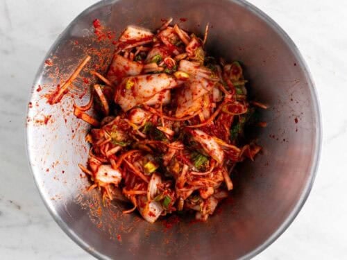 Col, rábano y cebolletas mezclados con la pasta de kimchi en un bol