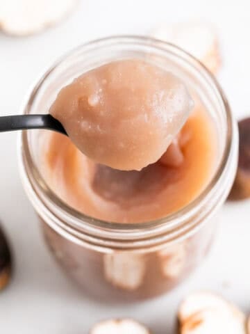 Cuchara con crema de castañas sobre un tarro de crema de castañas casera.