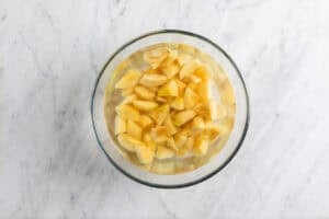 Membrillos pelados y troceados en un bol con agua.