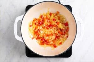 Cebolla, ajo y pimiento rojo salteados en una olla.