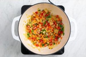 Cebolla, puerro, ajo, pimiento y zanahoria cocinados en una olla.