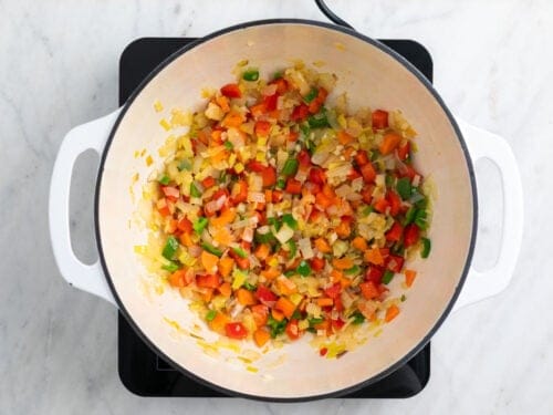 Cebolla, puerro, ajo, pimiento y zanahoria cocinados en una olla.