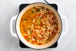 Ingredientes para hacer alubias blancas con verduras en una olla.